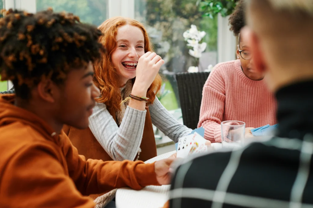 friends engrossed in a card game, their expressions reflecting a sense of safety and community that is crucial for healing from the intersections of trauma and eating disorders.