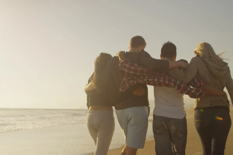 friends walk arm-in-arm on a beach, representing support in understanding bulimia nervosa vs binge eating disorder