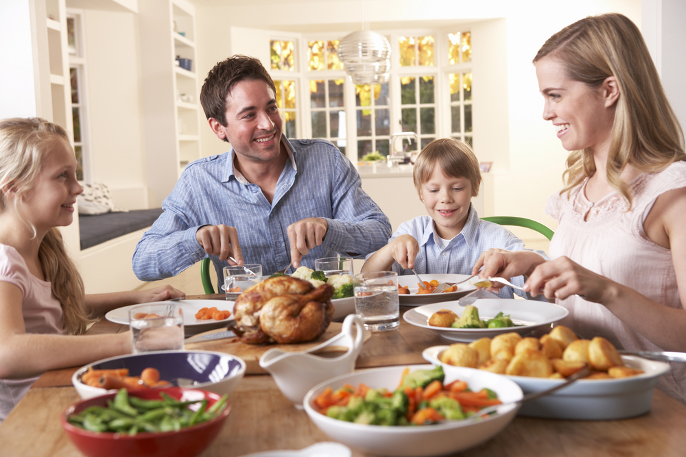 happy family having a roast chicken dinner at the table, showing positivity and freedom from toxic diet culture.