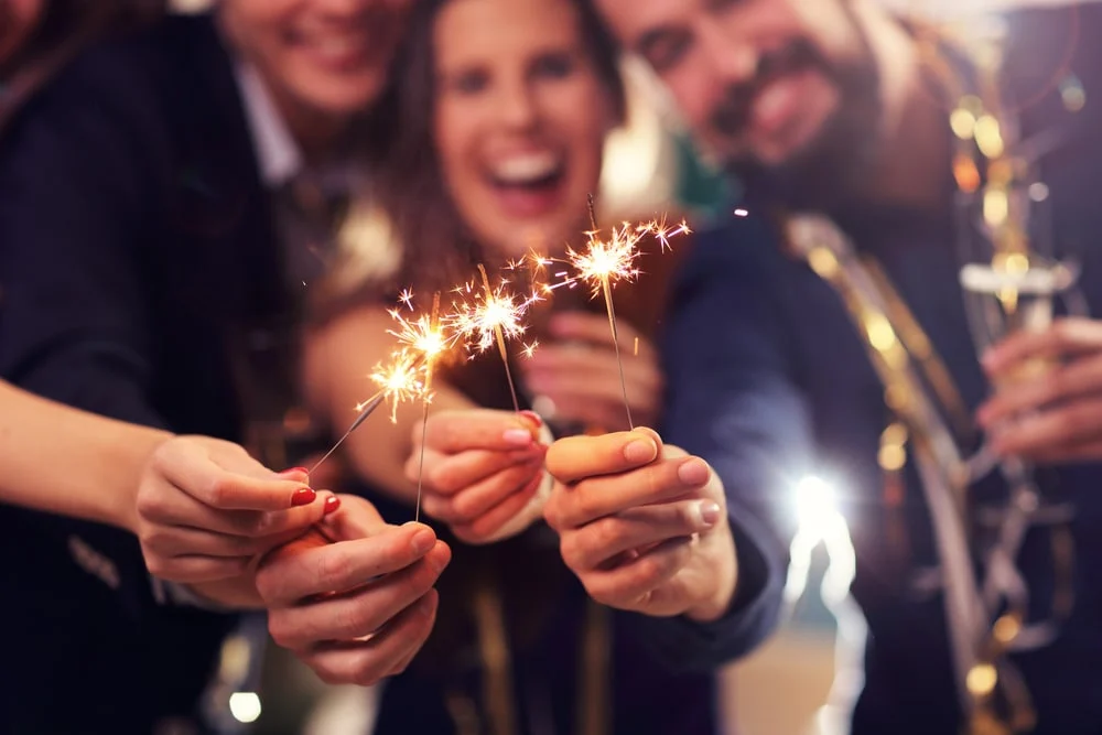 group of friends holding sparklers at a new year celebration, highlighting how social pressure can hide signs of orthorexia behind “wellness” goals.